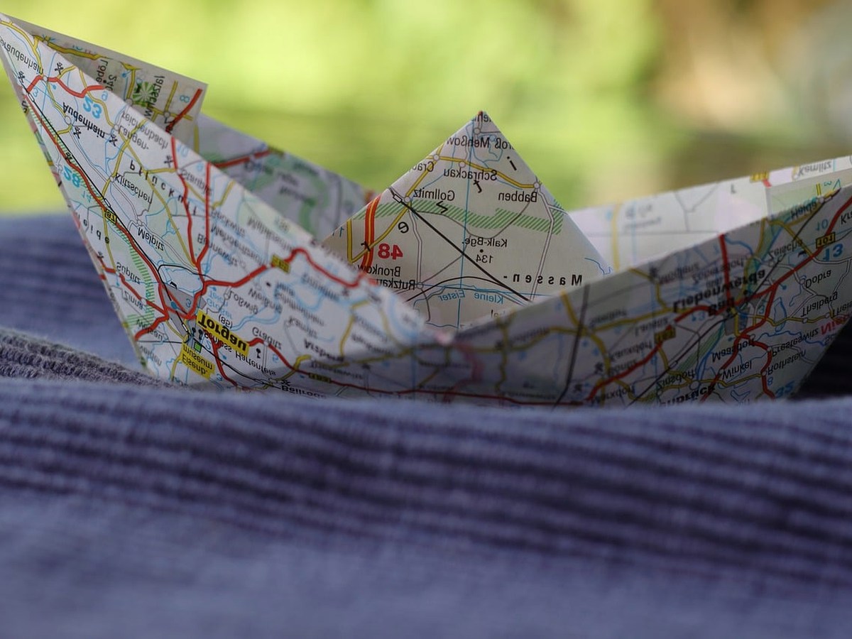 A folded paper map, a hand lamp and a stamped card on a wooden table at night.