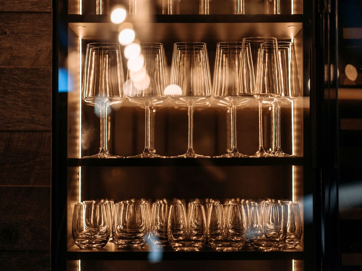 A crate-built bar front with glassware and a brass lamp, with a double bass resting beside it.